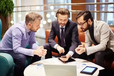 Tres colaboradores sentados en una sala observando un celular con Cisco Webex. 
